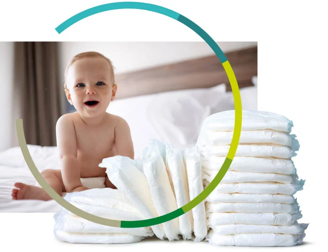Baby sitzt auf dem Bett. Im Vordergrund ein Stapel neu verpackter Windeln
